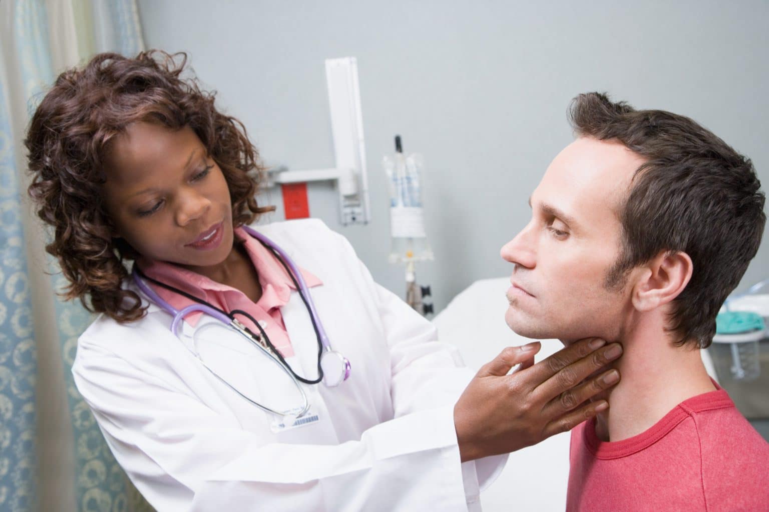 head-and-neck-cancer-evaluation Female doctor examines the outside of a male patient's throat.