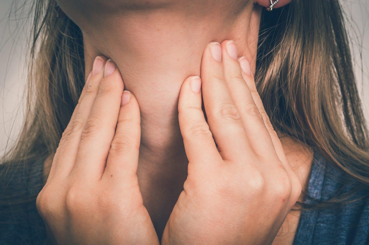 Sore-Throat-symptoms Close up of a woman with her finger tips on her neck checking her sore throat.